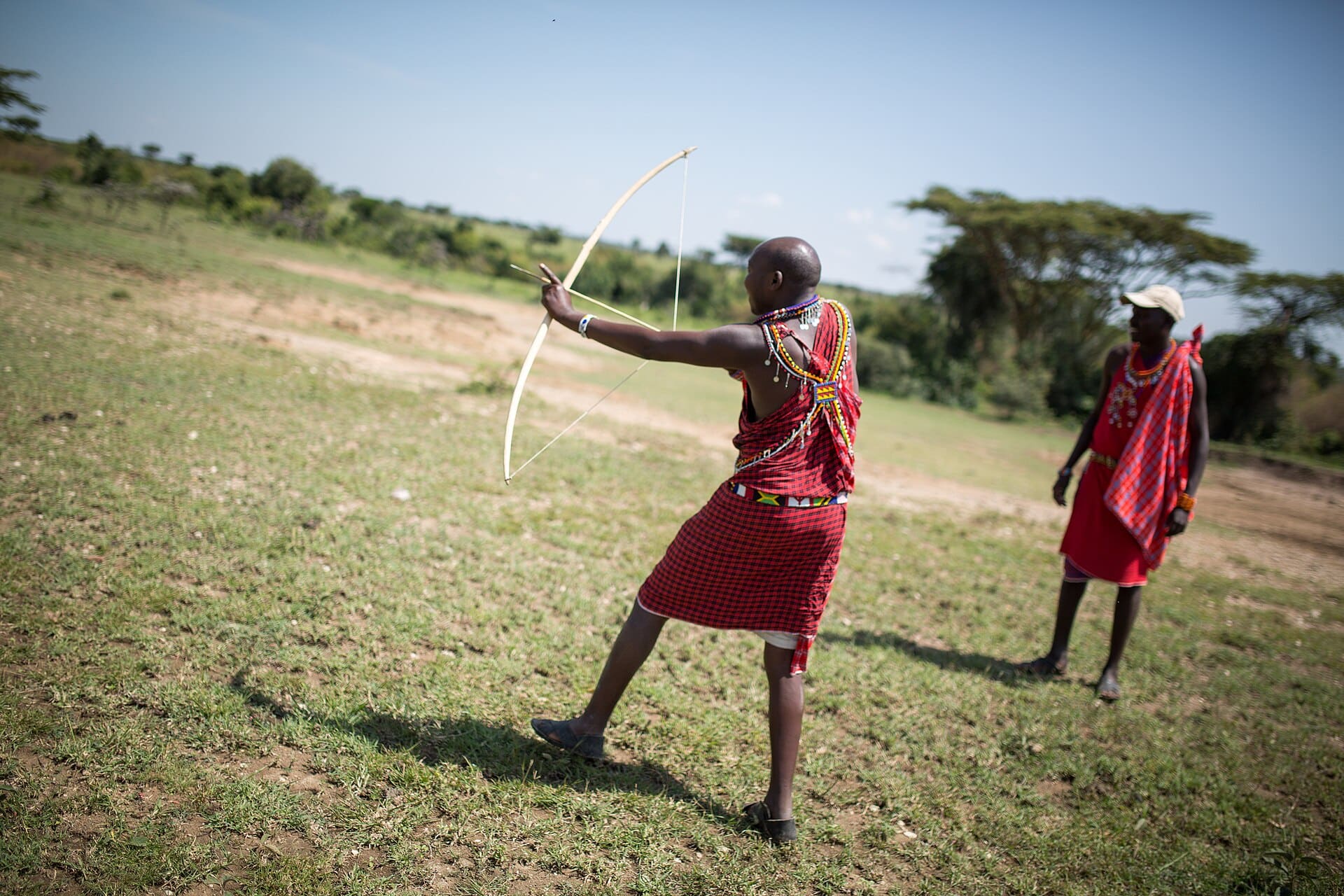 A Maasai guide in traditional dress drawing a bow during a walking safari in the Maasai Mara.